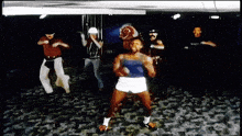 a group of men are dancing in a dark room and one of them is wearing a blue tank top