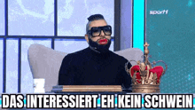 a man with a beard and red lips is sitting in a chair with a crown on his head .