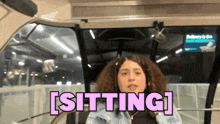 a woman is sitting in a car with the word sitting above her head