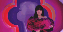 a woman wearing a pink fur coat is standing in front of a rainbow .