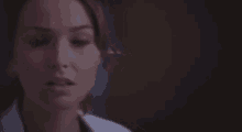 a close up of a woman 's face in a lab coat looking at the camera .