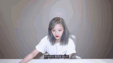 a woman with gray hair is sitting at a desk with korean writing on the bottom of her shirt