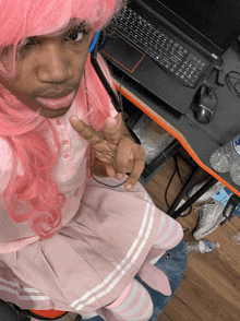 a man in a pink wig is sitting in front of a lenovo laptop