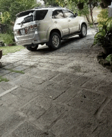 a silver suv is parked on a brick driveway with a license plate that says ' a ' on it