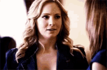 a woman in a denim jacket is talking to another woman in a room .