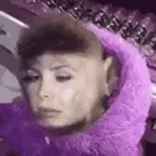 a close up of a woman 's face wearing a purple wig .