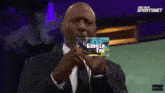a man in a suit holds up a picture of a gorilla that says gorilla tag on it