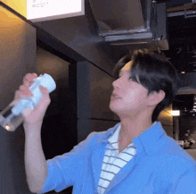 a man in a blue shirt is holding a spray bottle .