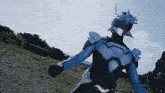 a person in a blue and black superhero costume is standing on a dirt road .
