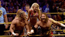 a group of wrestlers are standing in a ring and one of them is wearing a red and blue top