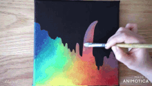 a person is painting a rainbow on a black canvas with the words made in animotica on the bottom