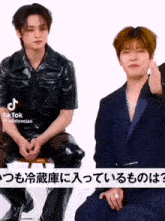 a man in a suit is sitting next to another man in a black jacket ..