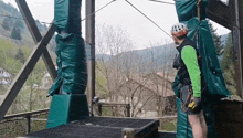 a man wearing a helmet and a green shirt is standing on a bridge