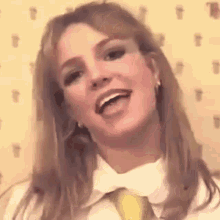 britney spears is wearing a white shirt and a yellow tie .