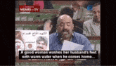 a man is giving a speech in front of a sign that says " a good woman washes her husband 's feet