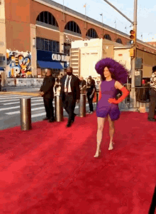 a woman in a purple dress walks on a red carpet in front of a building that says old navy