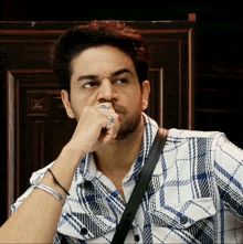 a man wearing a plaid shirt has a ring on his left hand