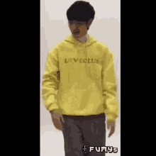a man wearing a yellow hoodie that says loveclub on it