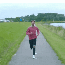 a man in a pink sweater is jogging down a path