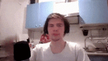 a man in a white shirt is standing in a kitchen with blue cabinets