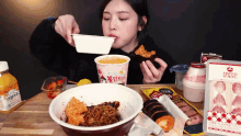 a woman is sitting at a table eating a bowl of food and a cup of soup