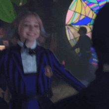 a girl with pink and blue hair is wearing a striped jacket and a bow tie with the letter w on it