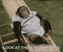 a chimpanzee is laying on a wooden slide with the words look at these monkey pj 's below it .