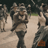 a group of people are walking down a road with the long walk written in orange