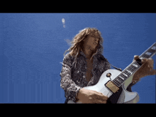 a man in a leopard print shirt is playing a white guitar