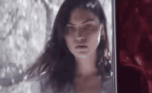 a woman is standing in front of a window and looking out .