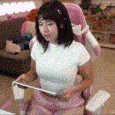 a woman sitting in a pink chair holding a tablet