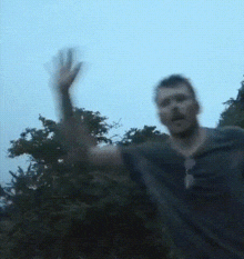 a man with a beard is waving his hand in the air