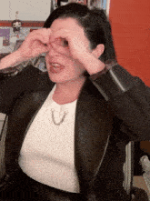 a woman covering her eyes with her hands while wearing a white shirt