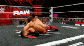 two men are wrestling in a wrestling ring with the word raw on the wall behind them .