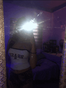 a woman taking a selfie in front of a mirror with a crop top that says abercrombie