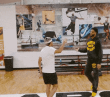 a man wearing a hoodie that says warriors on it talks to another man