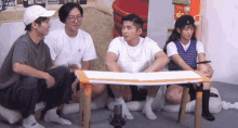 a group of people are sitting around a table and one of them is wearing a black hat