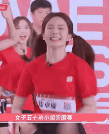 a woman in a red shirt is smiling and dancing in front of a crowd .