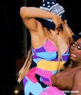 a woman in a colorful dress is holding another woman 's arm