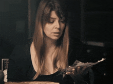 a woman is holding a piece of paper with the words what does all of this mean below her