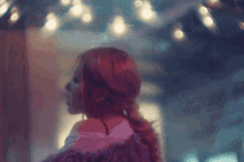 a woman with red hair is wearing a purple fur coat and looking at the camera .