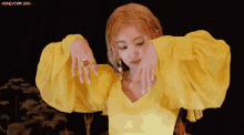 a woman wearing a yellow top and a ring with the words honeycam.org on the bottom right