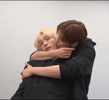 a man kisses another man on the cheek while they are hugging