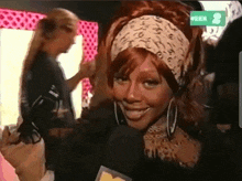 a woman wearing a headband and hoop earrings is smiling in front of a microphone with the number 8 in the background