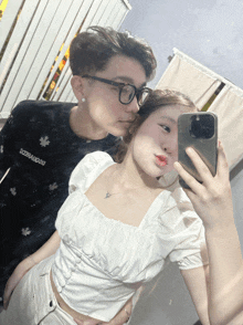 a woman taking a selfie with a man wearing a black shirt that says dsquared2 on it
