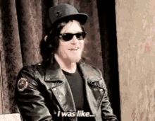 a man wearing sunglasses and a hat is sitting in front of a curtain and says i was like .