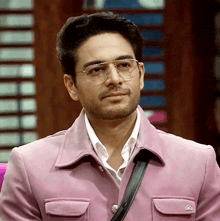 a man wearing glasses and a pink jacket with a black strap