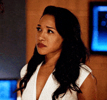 a woman in a white dress is standing in front of a television .