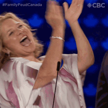 a woman is laughing with her arms in the air and the hashtag familyfeud canada is visible