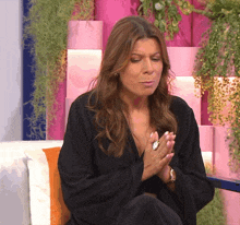 a woman is sitting on a couch with her hands folded in prayer